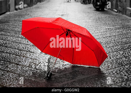 Red umbrella on cobblestone street in the old town. Wind and rain Stock Photo