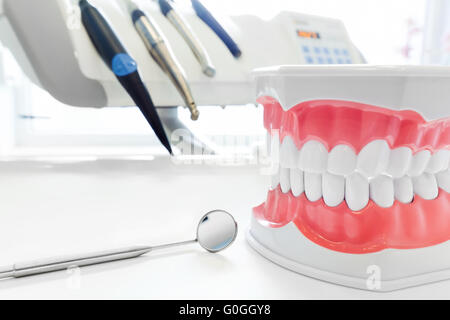 Clean teeth dental jaw model, mirror and dentistry instruments in dentist’s office. Stock Photo