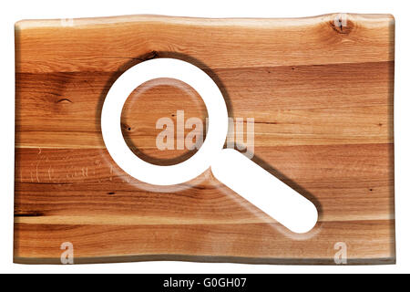 Magnifying glass symbol cut in wooden board isolated on white. Stock Photo