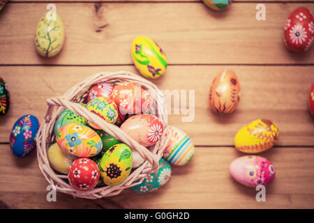 Colorful hand painted Easter eggs in basket and on wood. Handmade vintage decoration Stock Photo