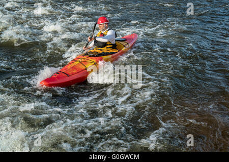 senior whitewater kayaker paddling upstream the river rapid Stock Photo