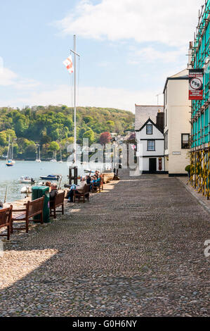 Shadows move across the cobblestone quay of Bayard's Cove Fort towards the visitors enjoying the view across the River Dart Stock Photo