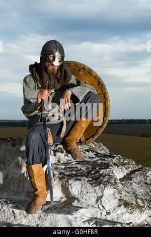 Knight sitting on a rock with a sword Stock Photo