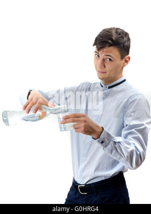 Teenager waiter pouring water from glass bottle into a glass isolated on white Stock Photo