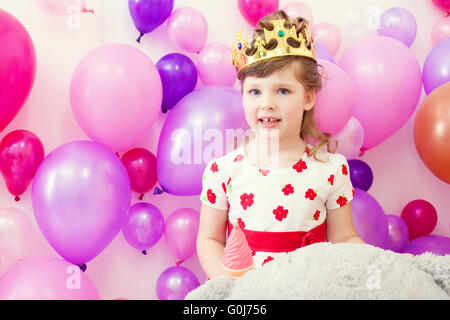 Cute girl posing in crown on balloons background Stock Photo