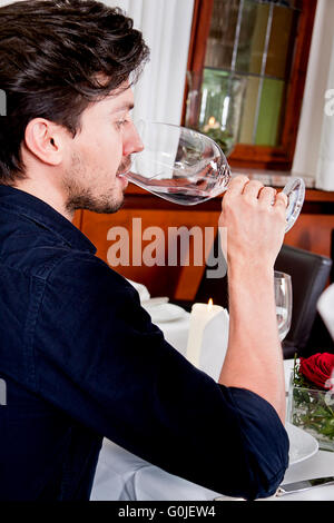 Male couple drinking red wine and kissing at home Stock Photo - Alamy