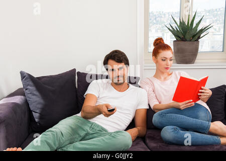 Sweet Couple Resting on Couch While Reading a Book Stock Photo