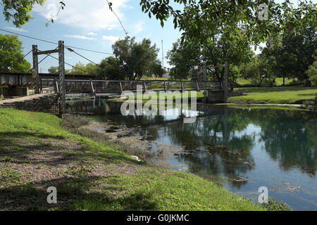 Suspension foot bridge crosses San Felipe Creek at Horse Shoe Park in Del Rio, Texas. Stock Photo
