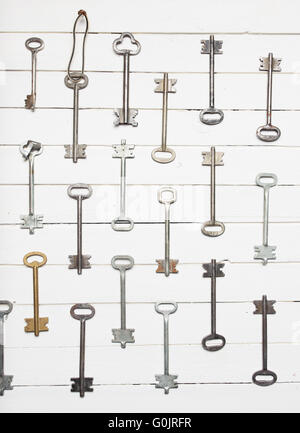 Some door keys aligned on old wooden surface, safety and security concept background Stock Photo