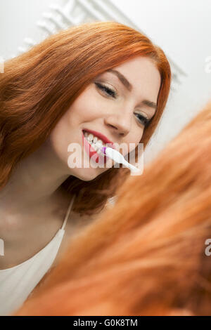 Woman Brushing her Teeth in Front a Mirror Stock Photo