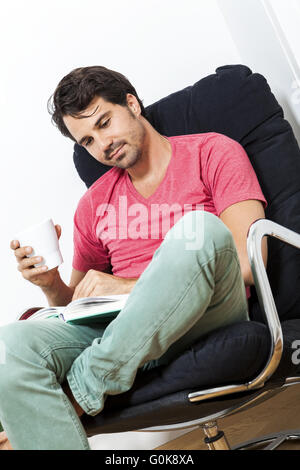 Man Sitting on Chair with Book and a Drink Stock Photo