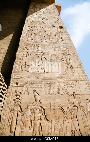 stone wall of Egyptian Edfu Temple of falcon god Horus, with carving figures and hieroglyphs, ceremony people, priest, pharaoh o Stock Photo