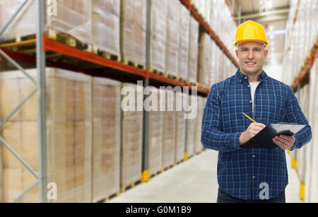 happy man in helmet with clipboard at warehouse Stock Photo