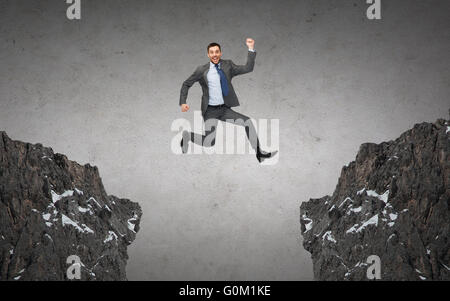 happy smiling businessman jumping between rocks Stock Photo