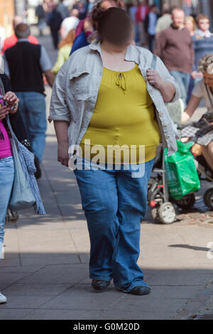 Overweight, obese woman in sports bra and leggings holding her