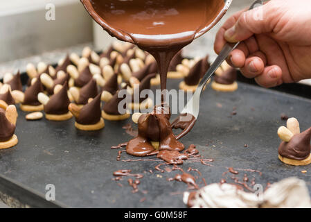 pastry chef covering the biscuits with melted chocolate Stock Photo