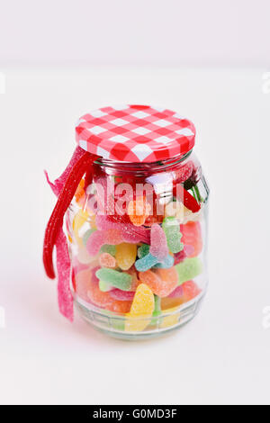 a glass jar full of different candies on a white surface Stock Photo