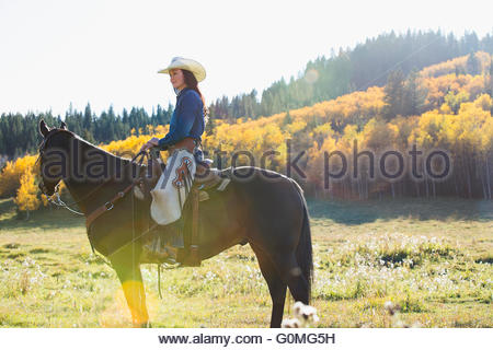 Woman sitting horseback in sunny autumnal field