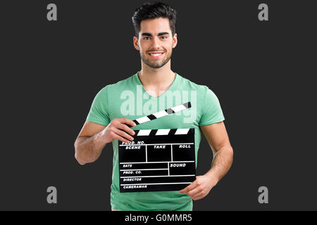 Portrait of handsome young man holding a clapboard, isolated on gray background Stock Photo
