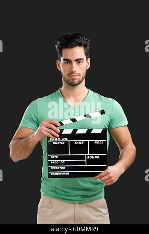 Portrait of handsome young man holding a clapboard, isolated on gray background Stock Photo