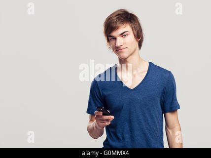 Portrait of handsome young man sending text messages with is mobile phone, over a gray background Stock Photo