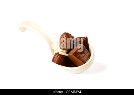 Ceramic spoon full of chocolate pralines isolated on white. Stock Photo