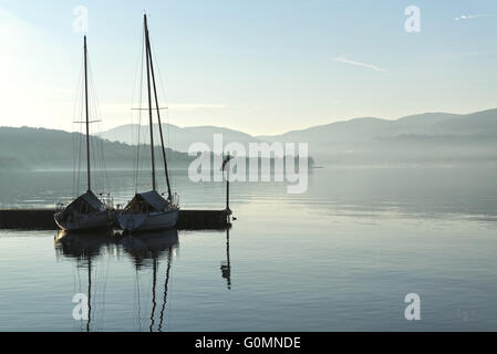 two boats in the harbor on a calm lake and the horizon mists of winter Stock Photo