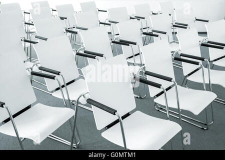 Rows of empty white modern chairs in a conference room Stock Photo