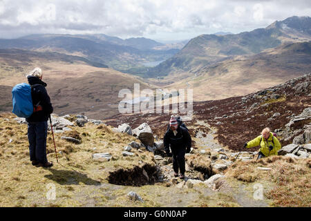 Three hikers ascending the Miners' Track up to Glyder Fach from Pen-y-Gwryd in valley below in Snowdonia National Park. Wales UK Stock Photo