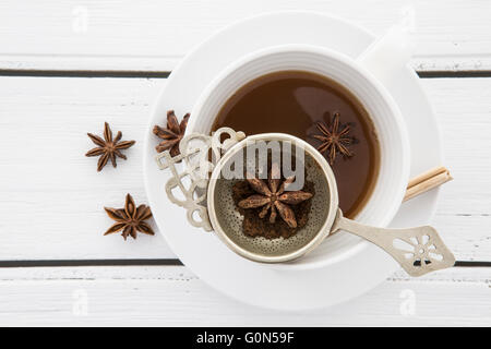 Cup of Tea with a vintage strainer and Star Anise on a rustic white wooden background Stock Photo