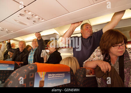 Air passengers getting their hand luggage from the overhead lockers on an Easyjet  flight from Southend airport to Malaga Spain Stock Photo