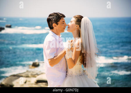Elegant smiling bride and groom walking on the beach, kissing, wedding ceremony, Mediterranean Sea. Stock Photo