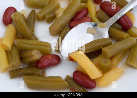 A very close view of three bean salad on a white plate with a spoon. Stock Photo