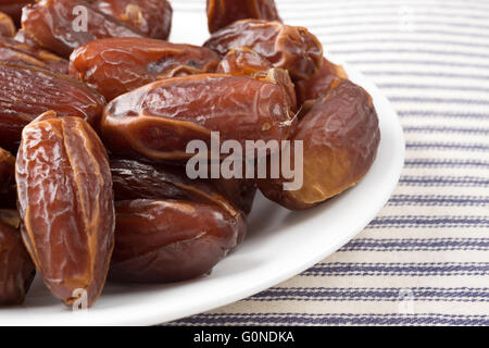 A close view of Tunisian pitted dates on a plate atop a striped table cloth. Stock Photo