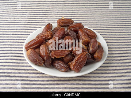 Tunisian pitted dates on a white plate atop a blue striped table cloth. Stock Photo