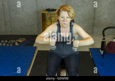 Mature woman in basement gym doing strength training. Stock Photo