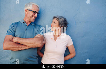 Portrait of affectionate mature couple looking at each other against blue background. Loving middle aged man and woman standing Stock Photo