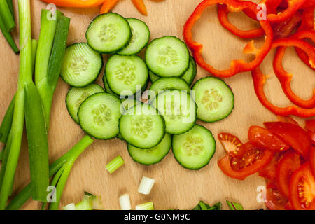 Freshly sliced English cucumber shot from above surrounded by other chopped vegetables Stock Photo
