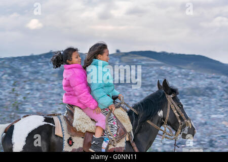 QUITO, ECUADOR, OCTOBER - 2015 - Two indigenous ecuadorian girls riding a horse at panecillo hill in Quito, Ecuador Stock Photo