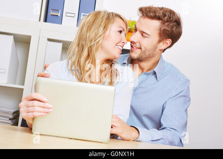 Young happy couple sitting with tablet PC in the living room Stock Photo