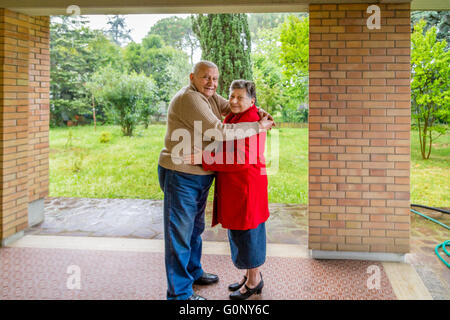 elderly couple hugging sitting on the sofa in their living room Stock Photo