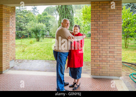 elderly couple hugging sitting on the sofa in their living room Stock Photo