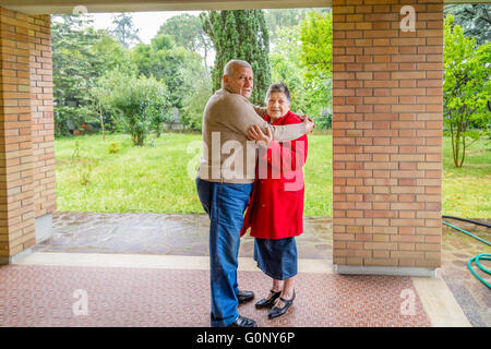 elderly couple hugging sitting on the sofa in their living room Stock Photo