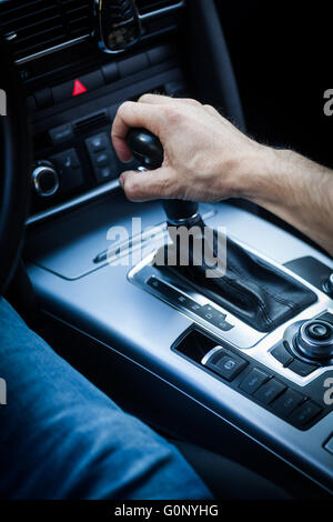 Detail of a hand pulling an automatic gear shifter in a new car. Stock Photo