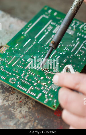 Man with soldering iron to solder electronic board. Stock Photo