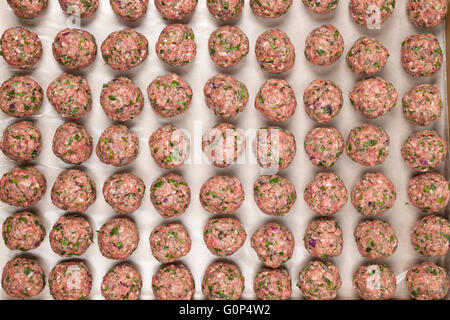 Rows of raw homemade meatballs prepared for cooking on a tray, overhead view Stock Photo