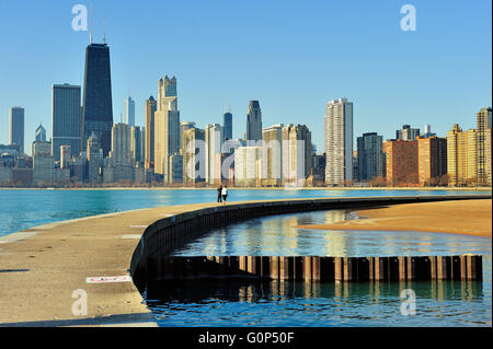 A couple walks along a breakwater that separates Lake Michigan from a small pool at Chicago's North Avenue Beach. Chicago, Illinois, USA. Stock Photo