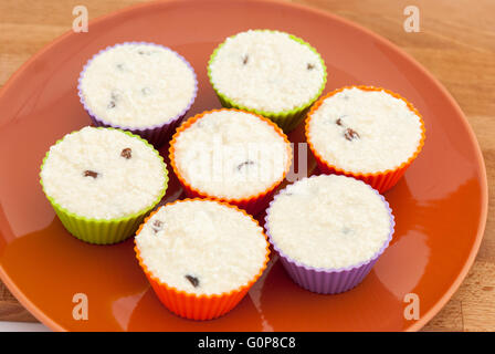 Cooking cheese and vanilla syrniki as cupcakes or muffins, in colored muffins cups closeup. Stock Photo