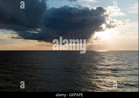 Dark clouds hiding sun over sea Stock Photo