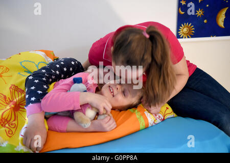 Sisters Skady-Lee (10) and Lucy-Mae (6) lie on a bed next to their mother Wiebke Ruedig at the night nursery at the Kapernaum daycare center in Flensburg, Germany, 03 May 2016. The first night nursery in Schleswig-Holstein has opened in Flensburg. Requirements for the parents at the service nursery at the Diako Hospital are strict: children may not stay for 24 hours at a time or be brought in the middle of the night. Photo: CARSTEN REHDER/dpa Stock Photo